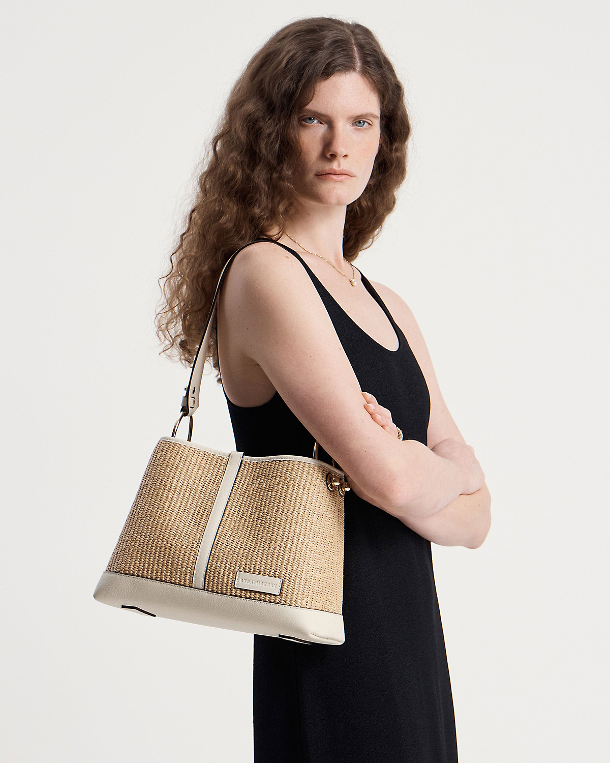 Model wearing Strathberry Lana Hobo bag in vanilla natural raffia on shoulder.