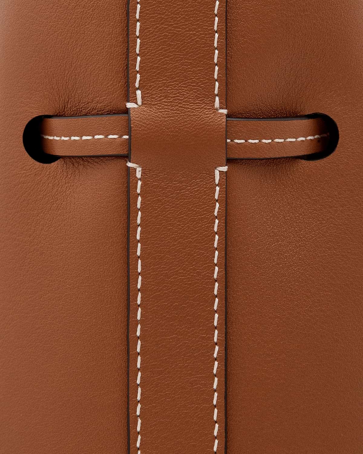 Chestnut leather strap threaded through slot with contrasting white stitching.