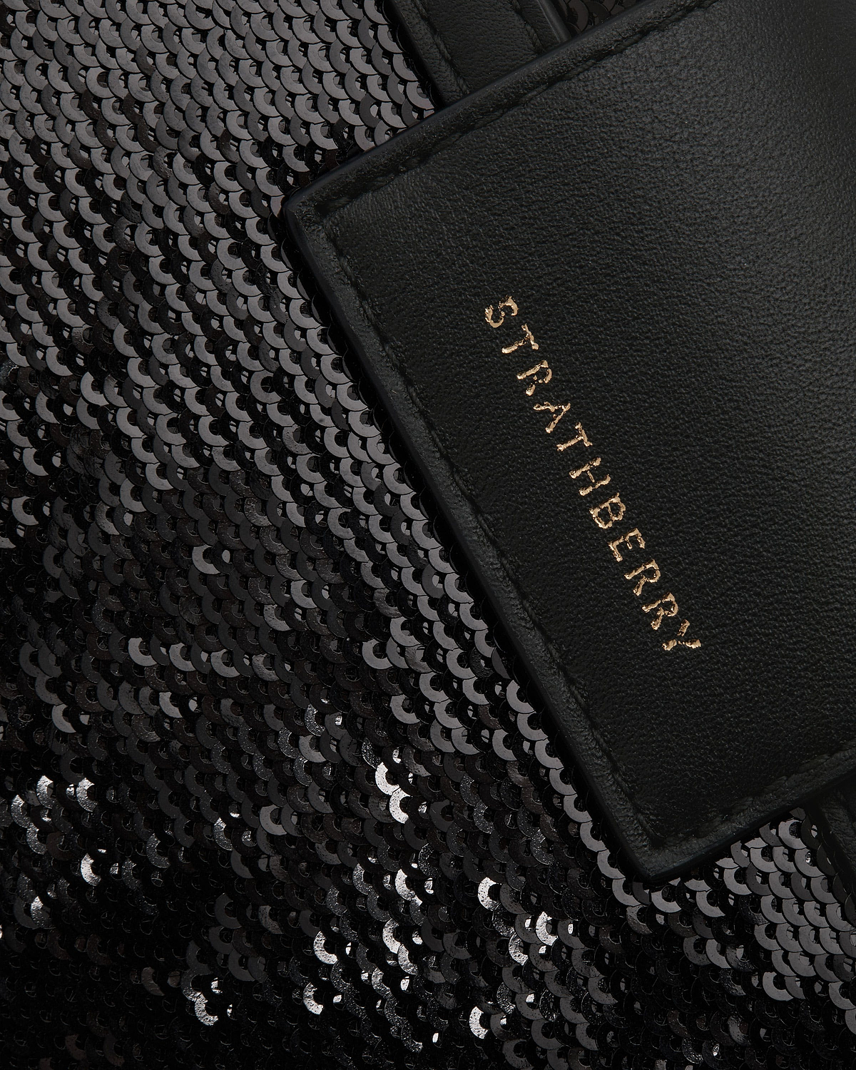 Black sequin crescent bag with leather trim and gold Strathberry logo visible