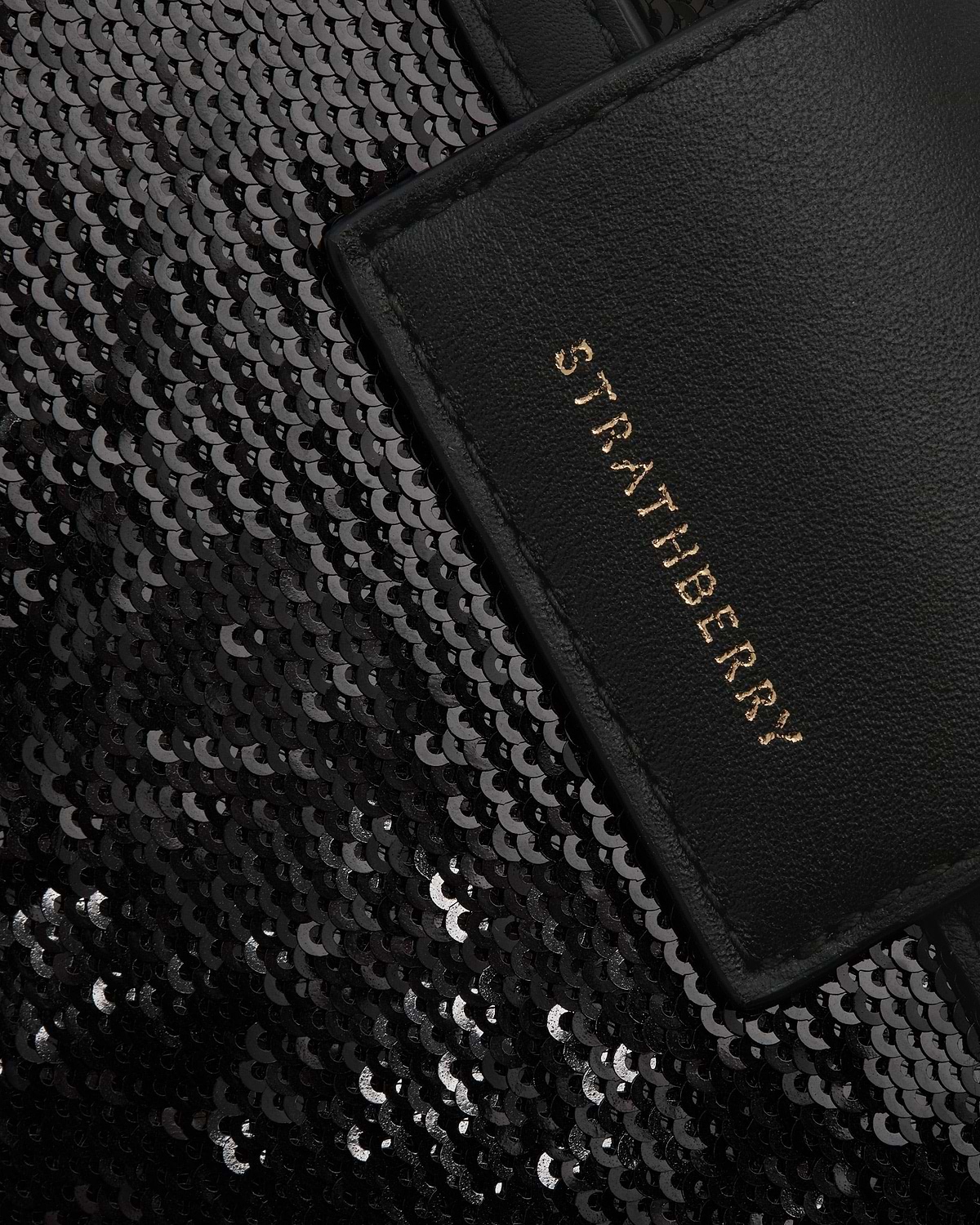 Black sequin crescent bag with leather trim and gold Strathberry logo visible