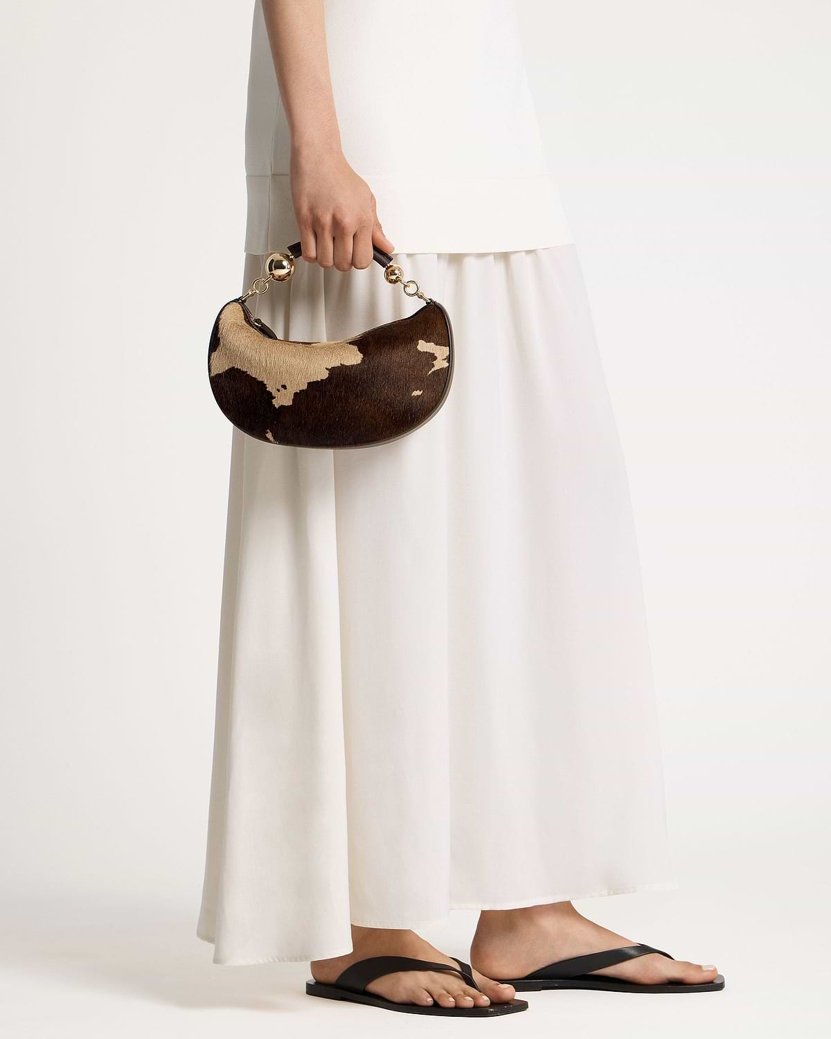 Crescent-shaped mini bag in sand and espresso spot print with gold ball handle.