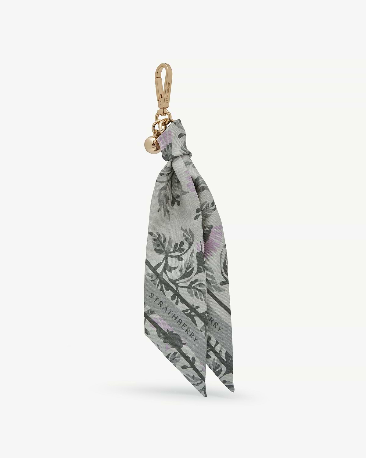 Strathberry silk charm in green thistle print tied to a gold clasp with logo disc.