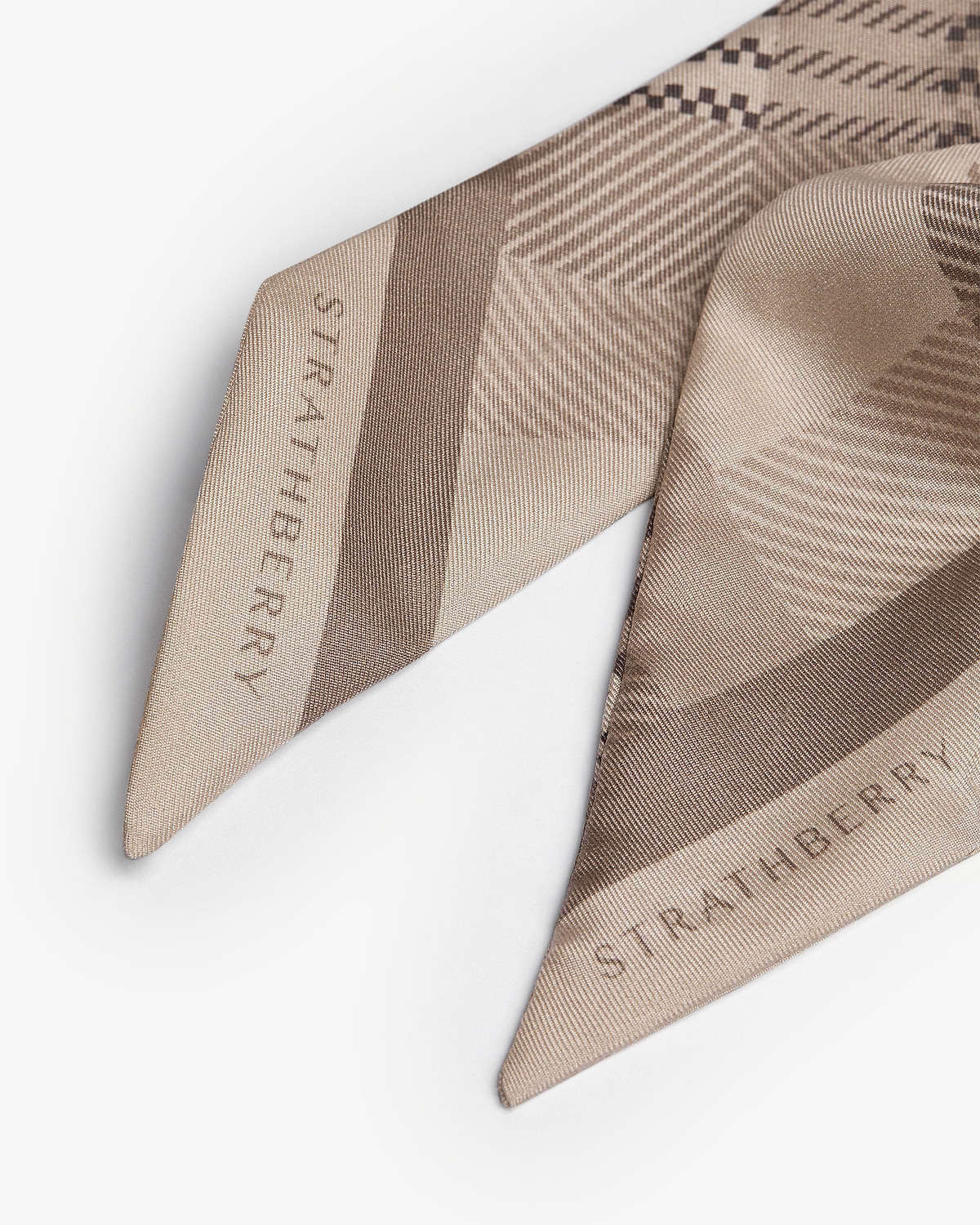 Silk skinny scarf in oat tartan showing Strathberry wordmark, folded close-up.