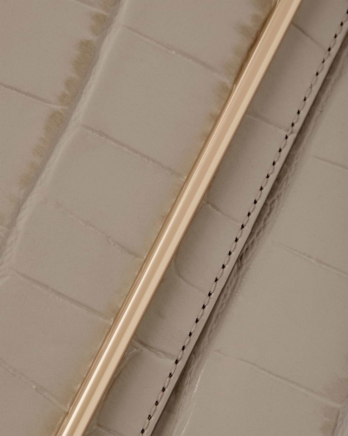 Croc-embossed leather strap with gold metal bar and stitched seam.