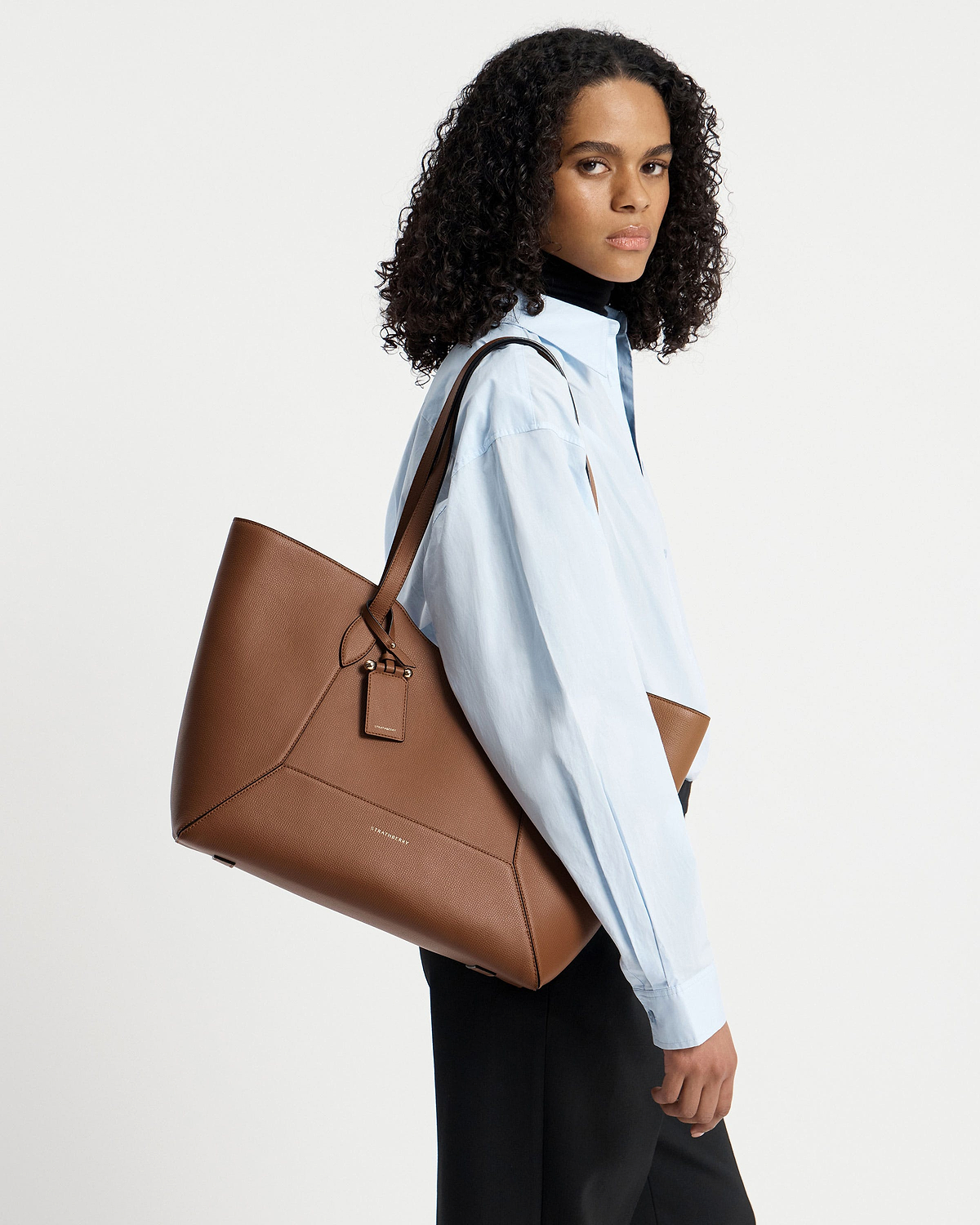 Model wearing Strathberry hazelnut Mosaic Cabas tote over shoulder, light blue shirt.