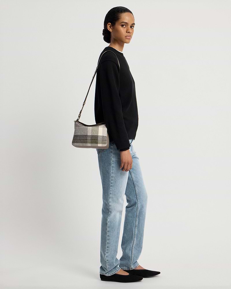 Model wearing checked tartan taupe shoulder bag with black jumper and jeans.