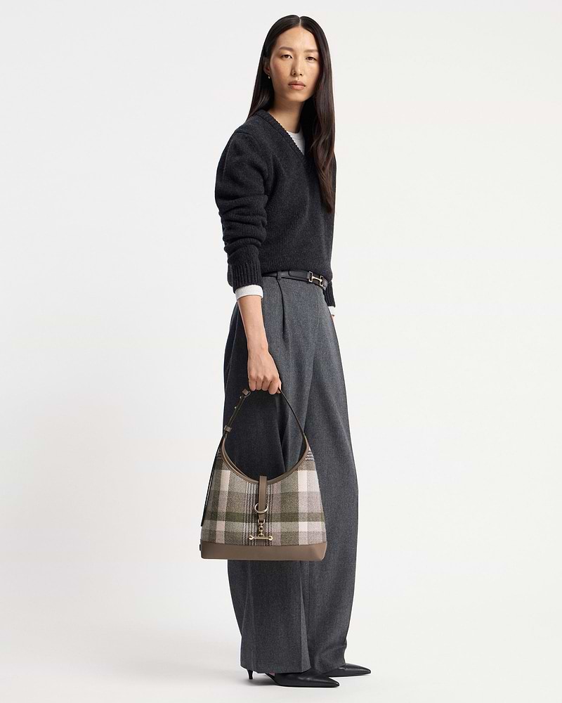 Model holding tartan taupe kite hobo bag with leather trim and gold hardware