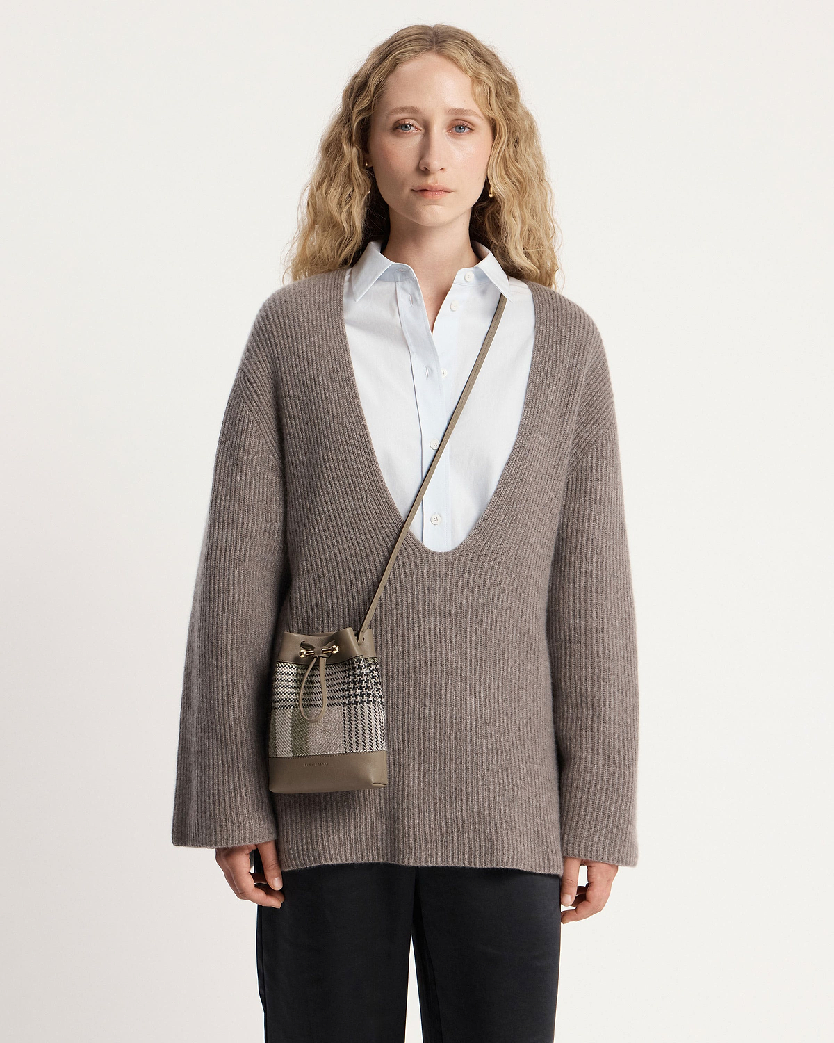 Woman wearing Strathberry Osette midi pouch in tartan taupe across body.