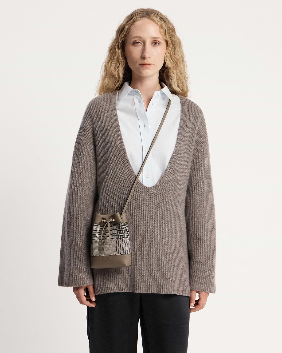 Woman wearing Strathberry Osette midi pouch in tartan taupe across body.