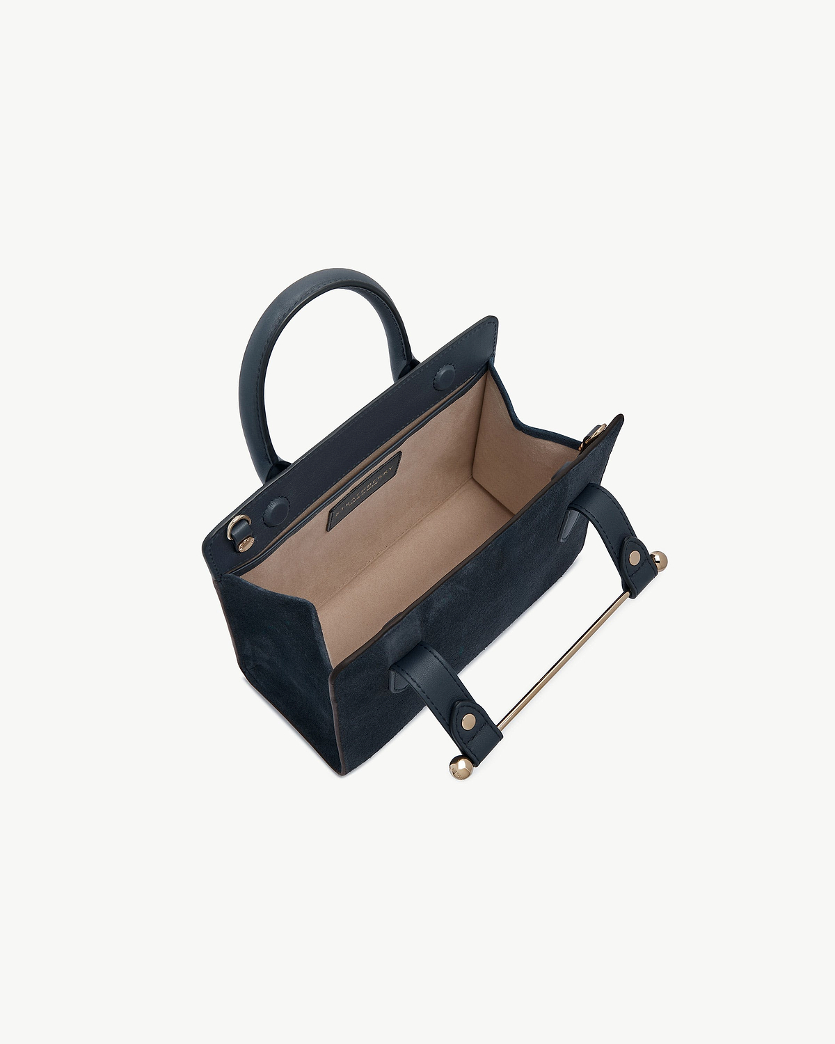 Navy suede mini tote showing beige interior, top handles and gold hardware.