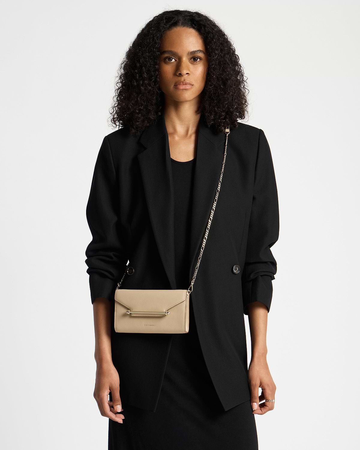 Model wearing black blazer with sand-coloured Multrees chain wallet on a gold chain.