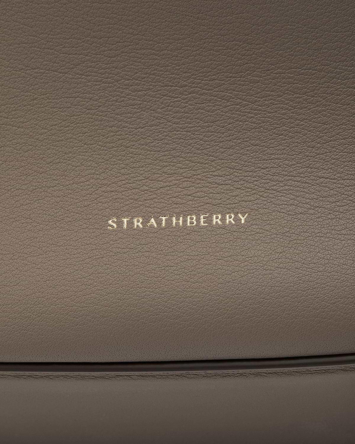 Taupe pebbled leather with gold Strathberry logo and stitched seam details.