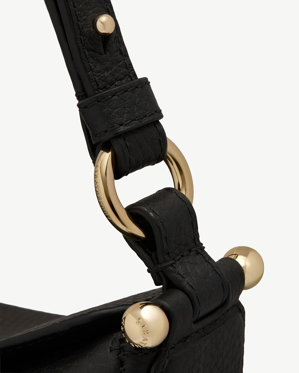 Black leather strap with gold Strathberry ring hardware and studs.