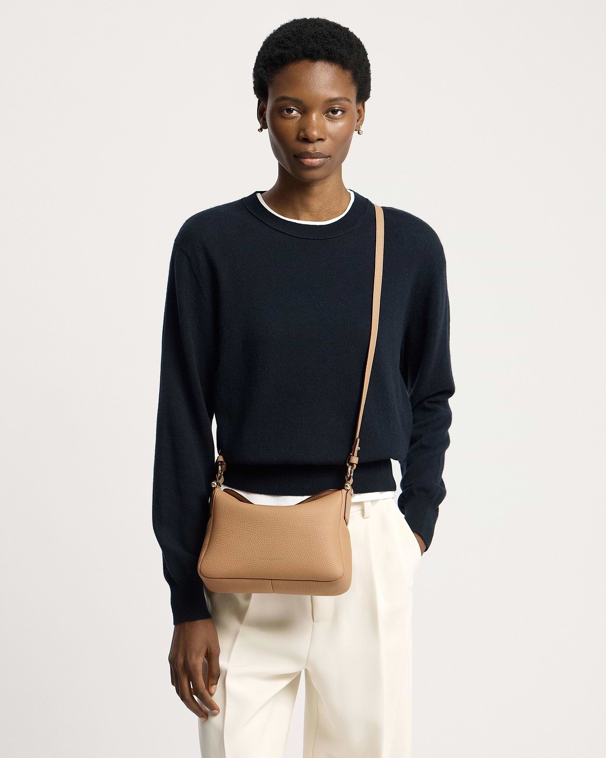 Model wearing a caramel Sway leather shoulder bag crossbody with navy jumper