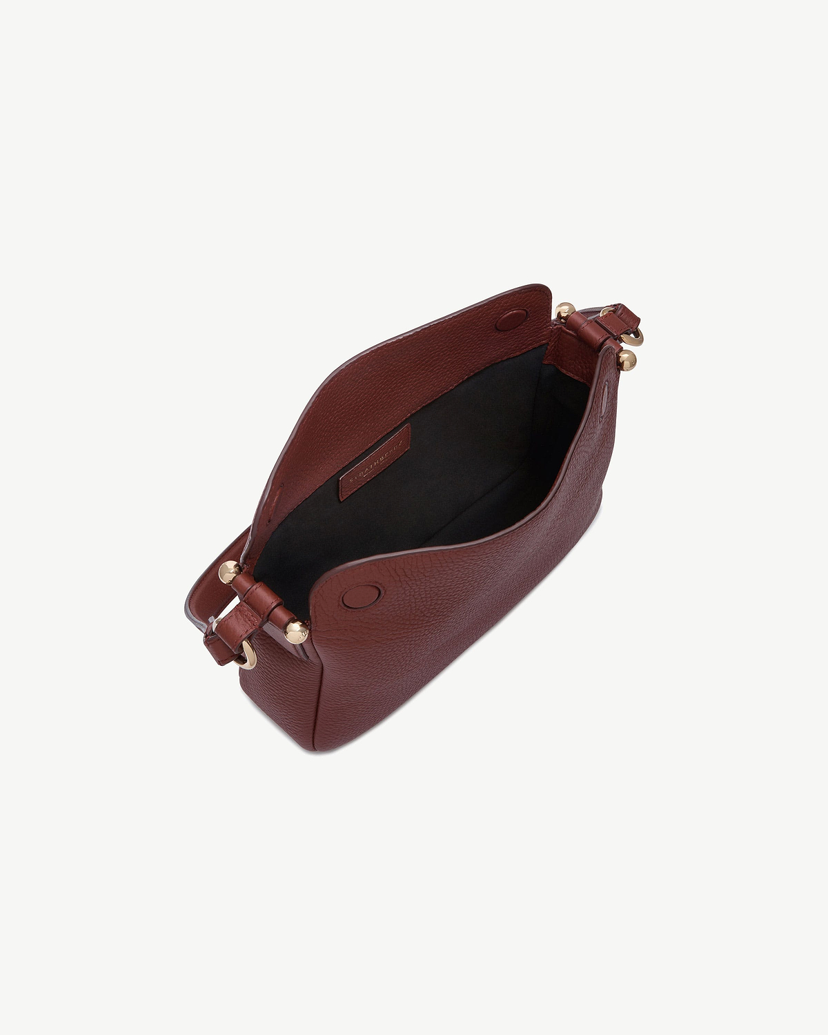 Strathberry Sway bag in oxblood, open top showing black lining and gold hardware.