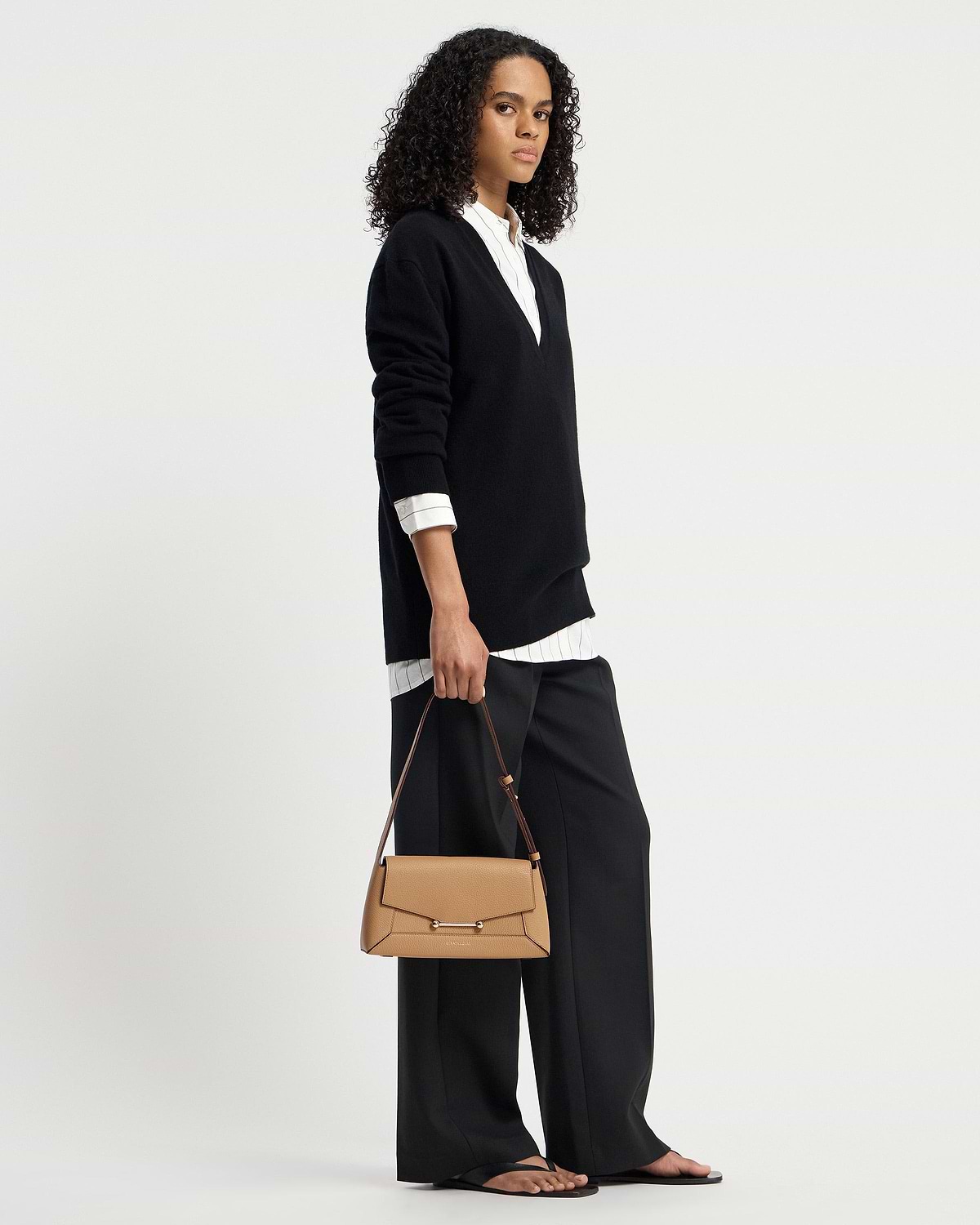 Model holding caramel mosaic shoulder bag with top handle and long strap.