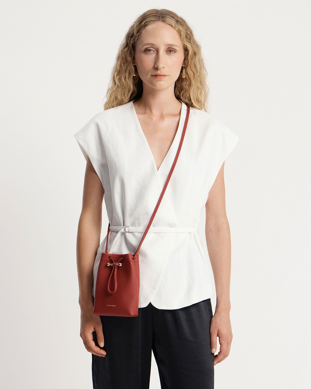 Woman in white top wearing Levanto red Osette Midi Pouch crossbody