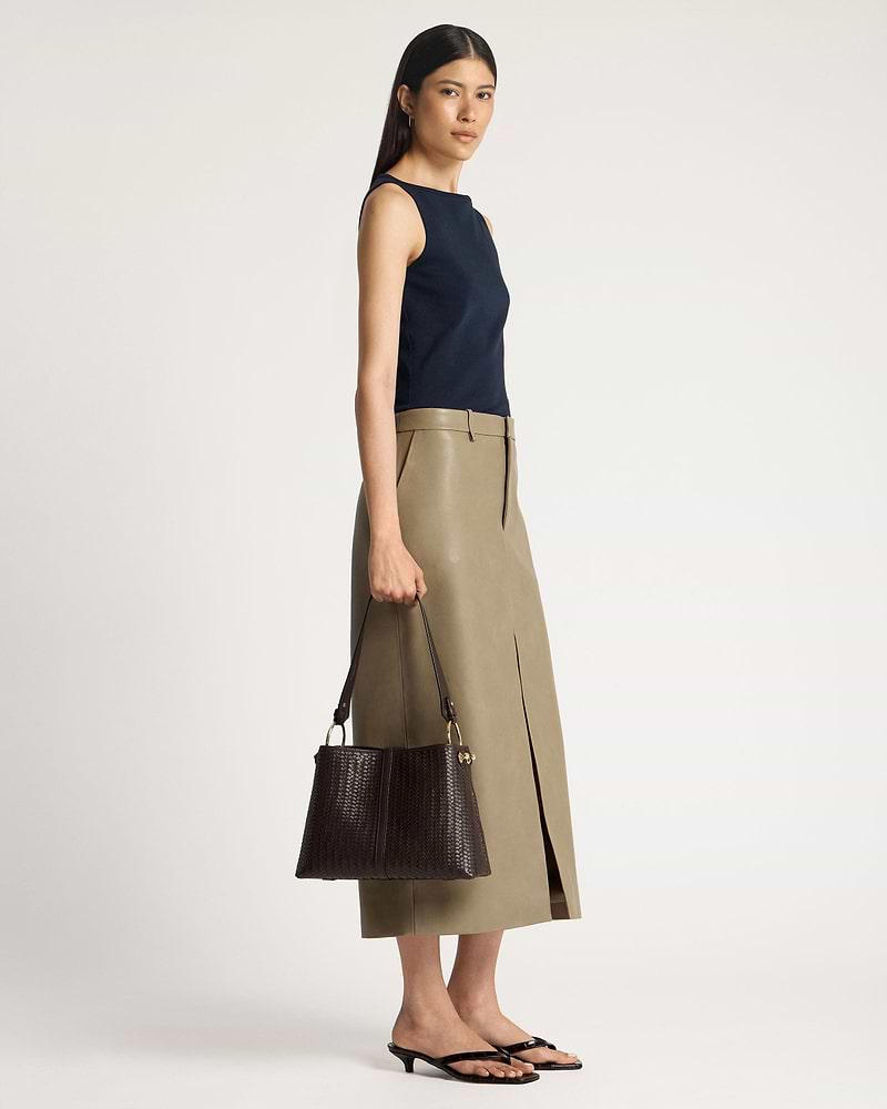 Model holding a chocolate woven leather hobo bag at her side.