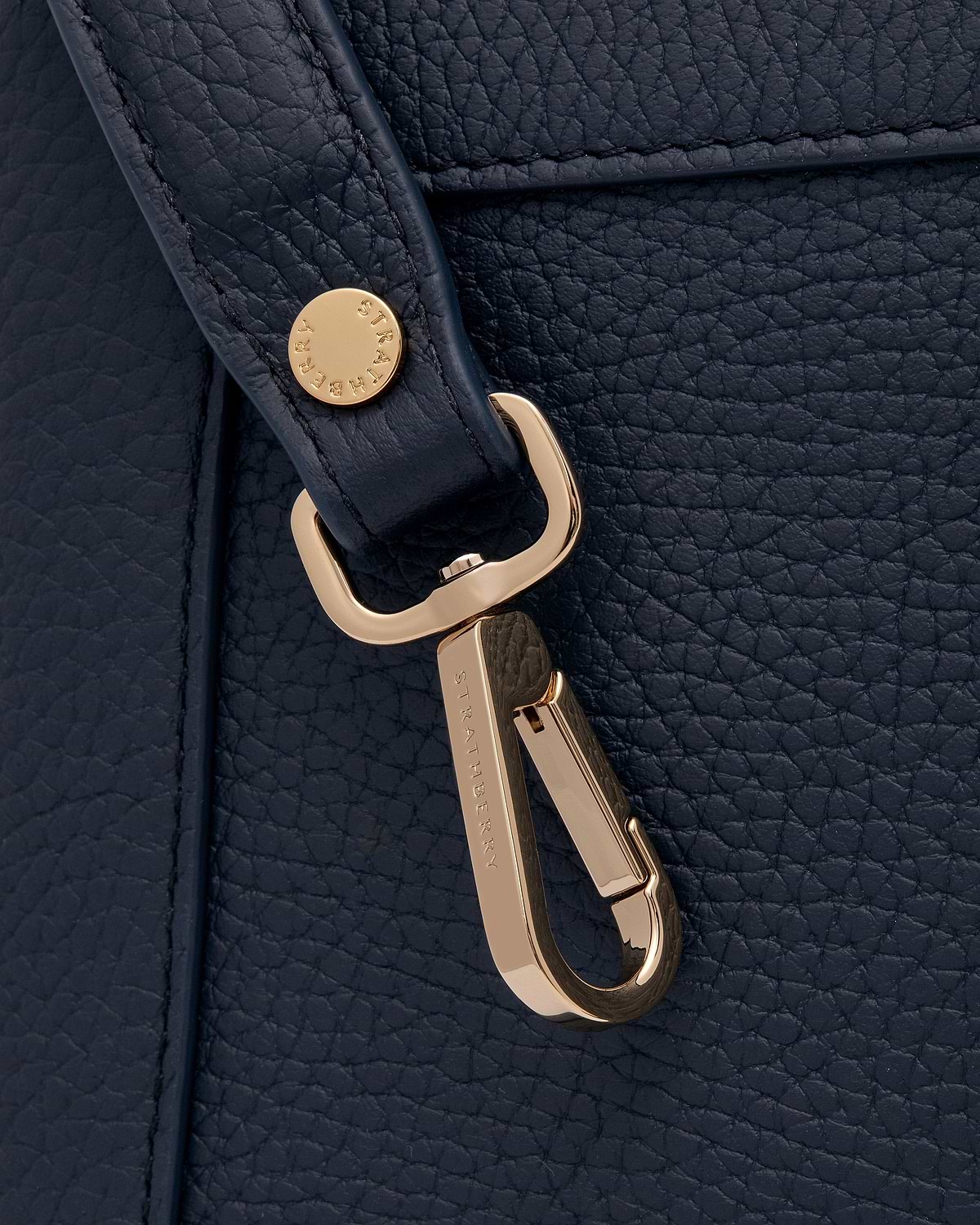 Navy pebbled leather bag strap with gold Strathberry clasp detail.