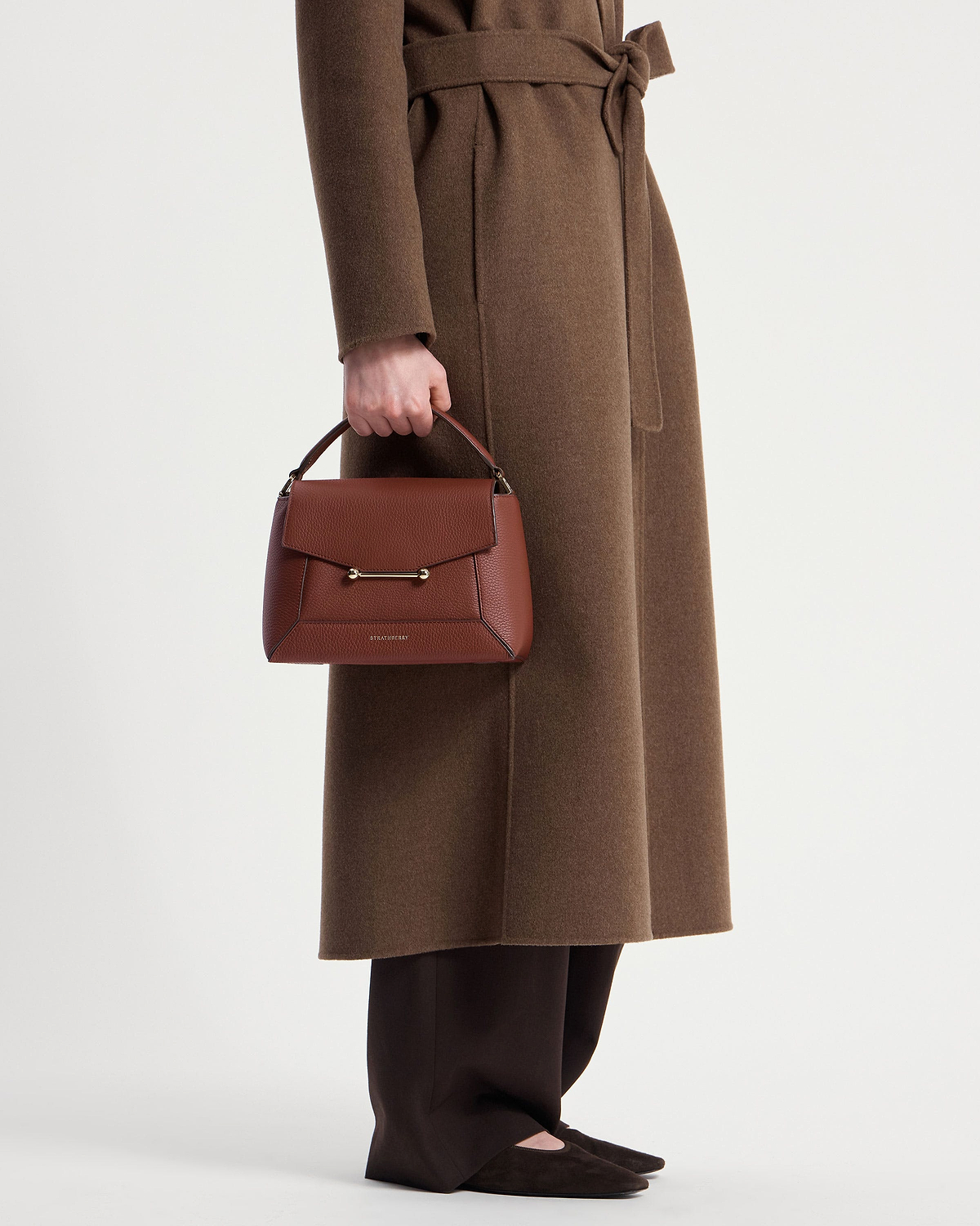 Model waist down holding a walnut mosaic bag with Strathberry logo.
