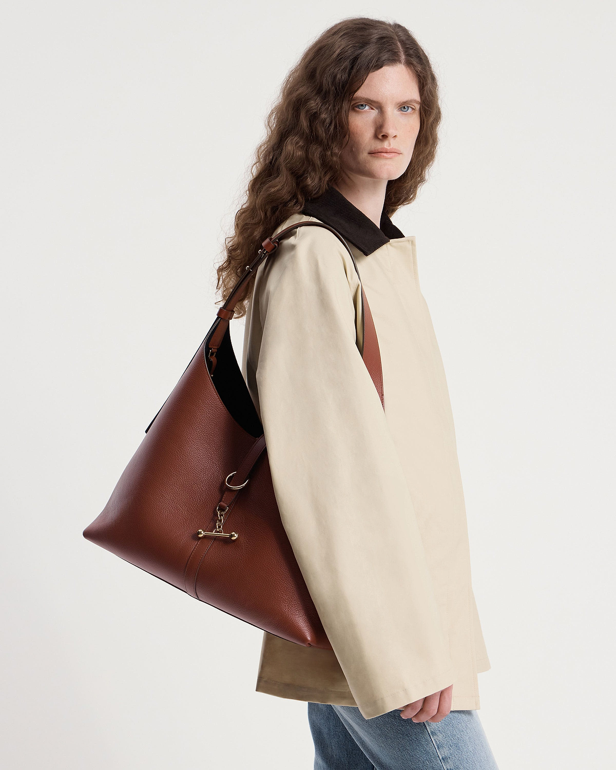 Woman in beige coat carrying a walnut leather Kite Hobo Maxi bag over her shoulder.