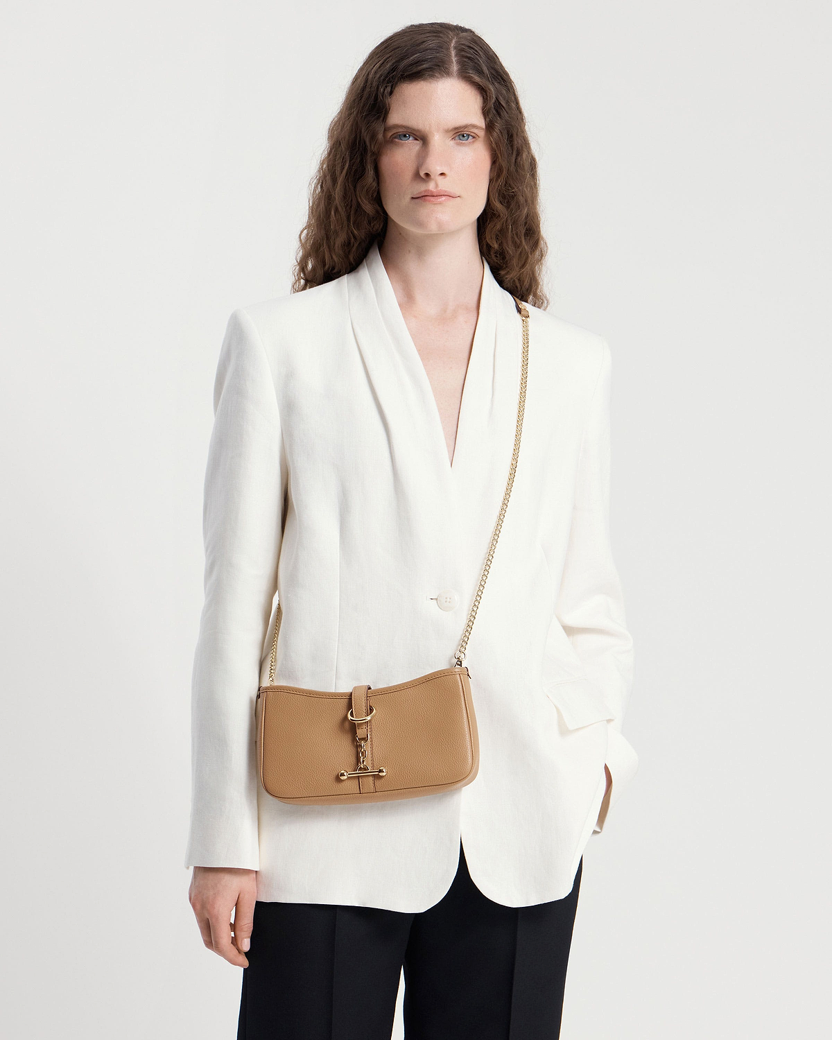 Model in a white blazer wearing a caramel leather Kite on a Chain bag