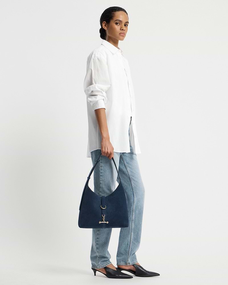 Model wearing a white shirt and jeans holding a loch blue suede Kite Hobo bag.