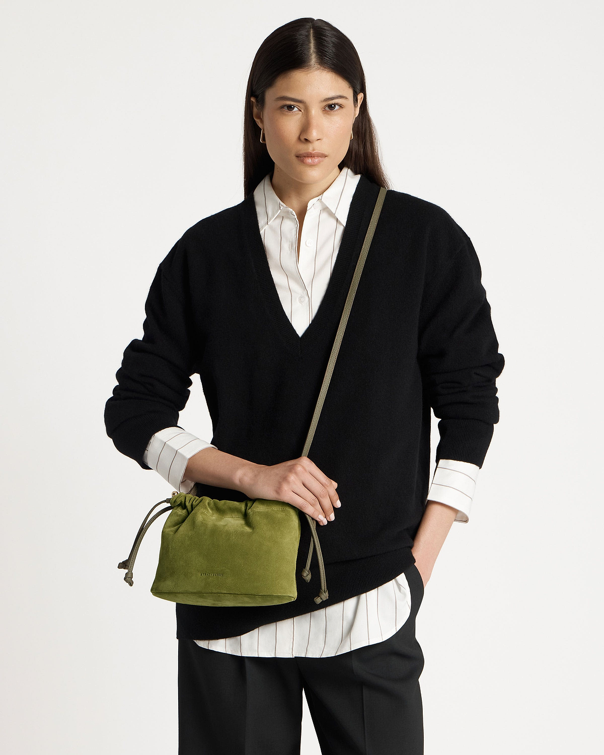 Model wearing black jumper holding lime suede drawstring bag with khaki strap.