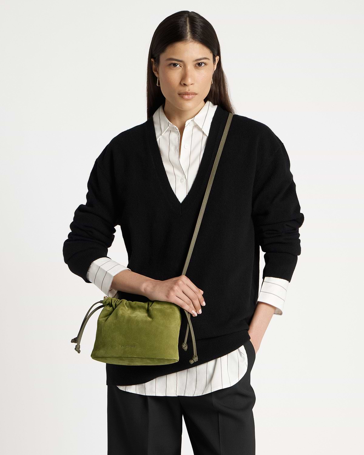 Model wearing black jumper holding lime suede drawstring bag with khaki strap.