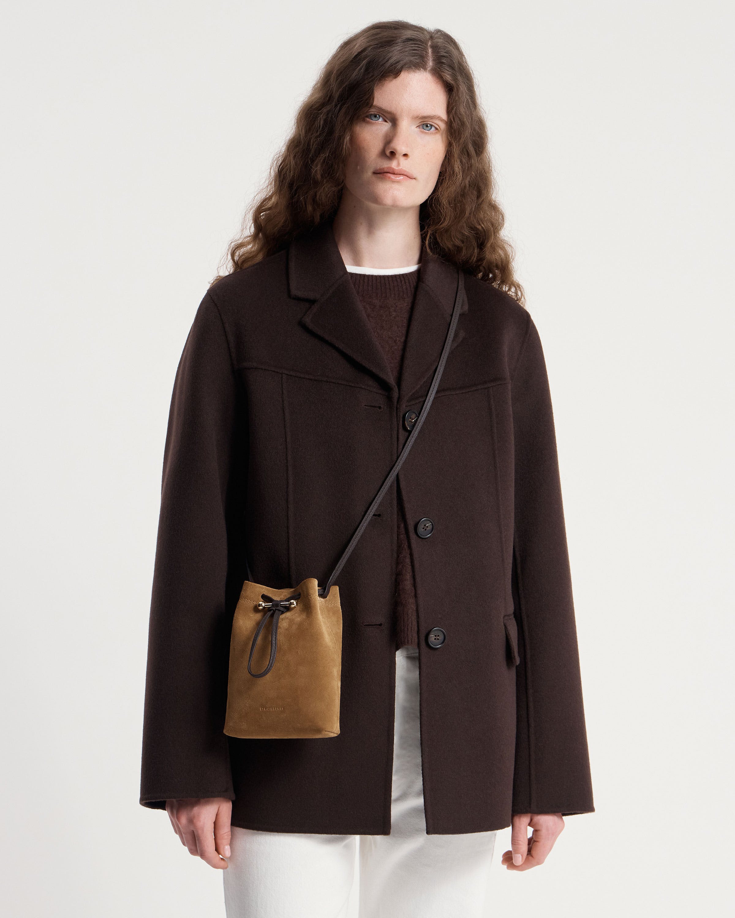 Model wearing Strathberry Osette midi pouch in toffee suede with espresso strap.