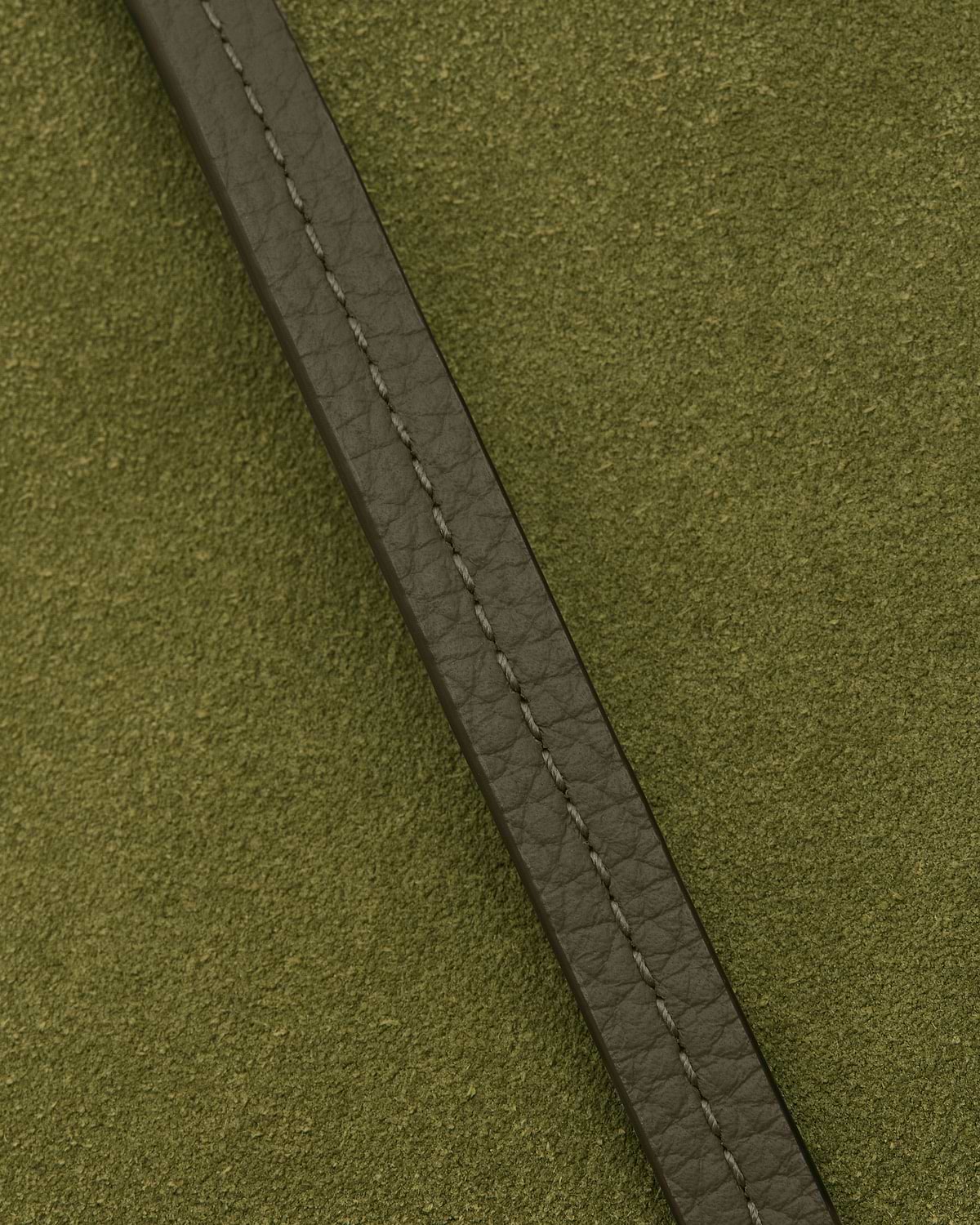 Khaki leather strap with stitching on lime suede textured pouch surface.