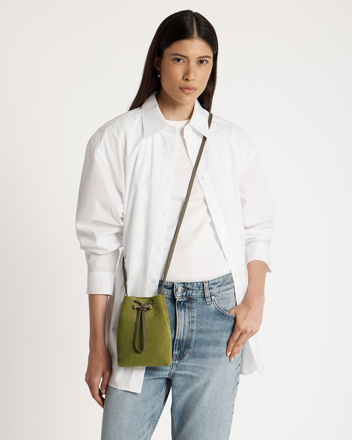 Model wearing white shirt and jeans with lime suede drawstring pouch and khaki strap.