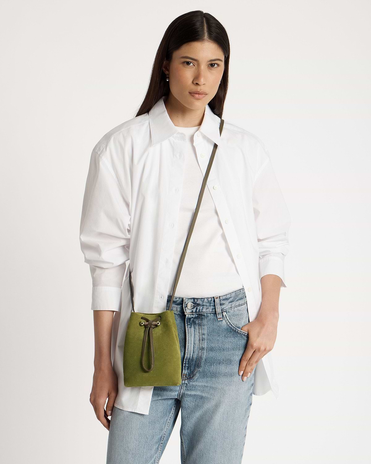 Model wearing white shirt and jeans with lime suede drawstring pouch and khaki strap.