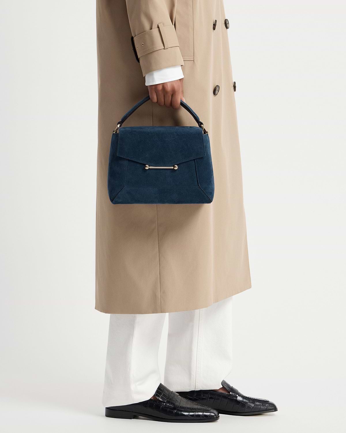 Loch blue suede mosaic bag with top handle, held against a beige coat.