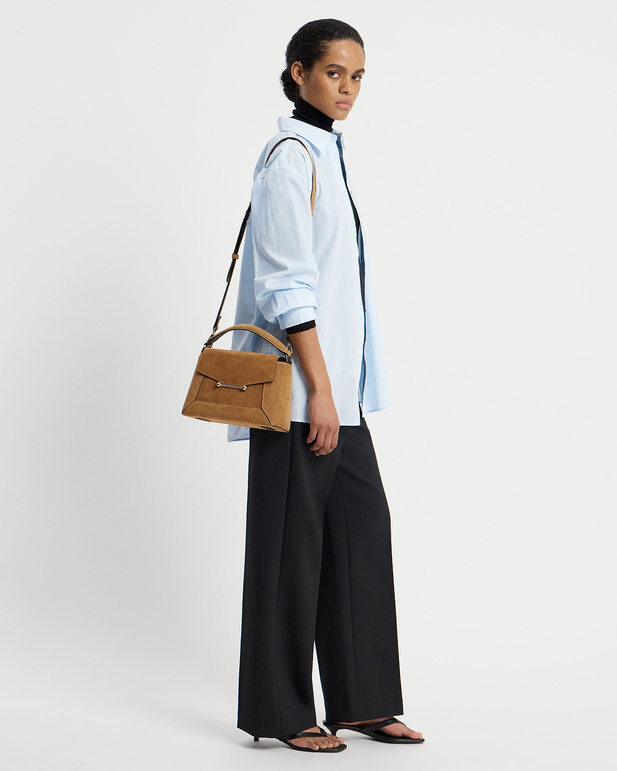 Woman wearing light blue shirt carrying toffee suede mosaic bag with espresso strap.