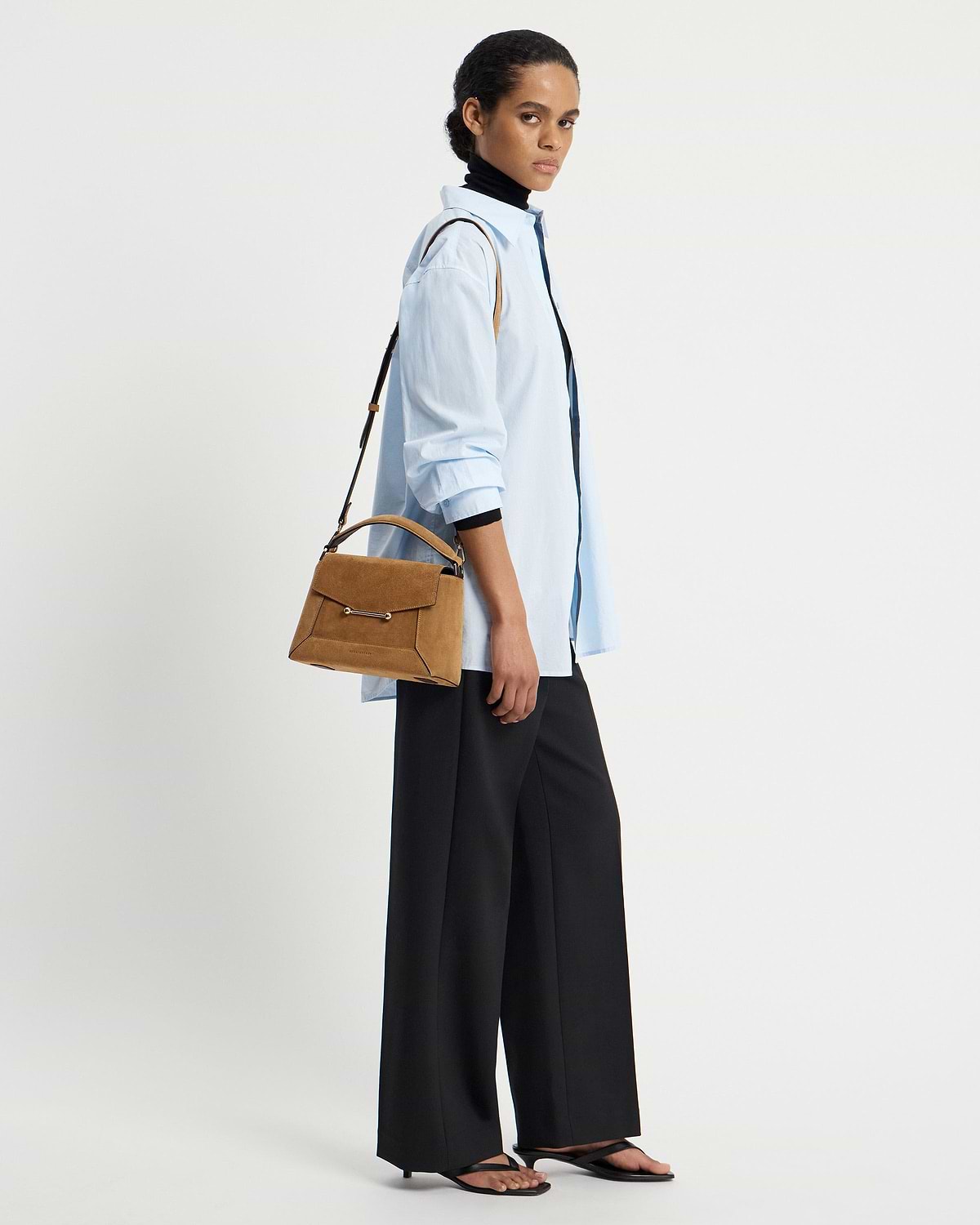 Woman wearing light blue shirt carrying toffee suede mosaic bag with espresso strap.