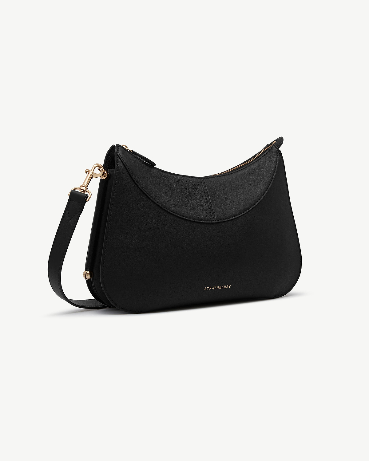 Black Nest shoulder bag with curved top flap, gold hardware, Strathberry logo.