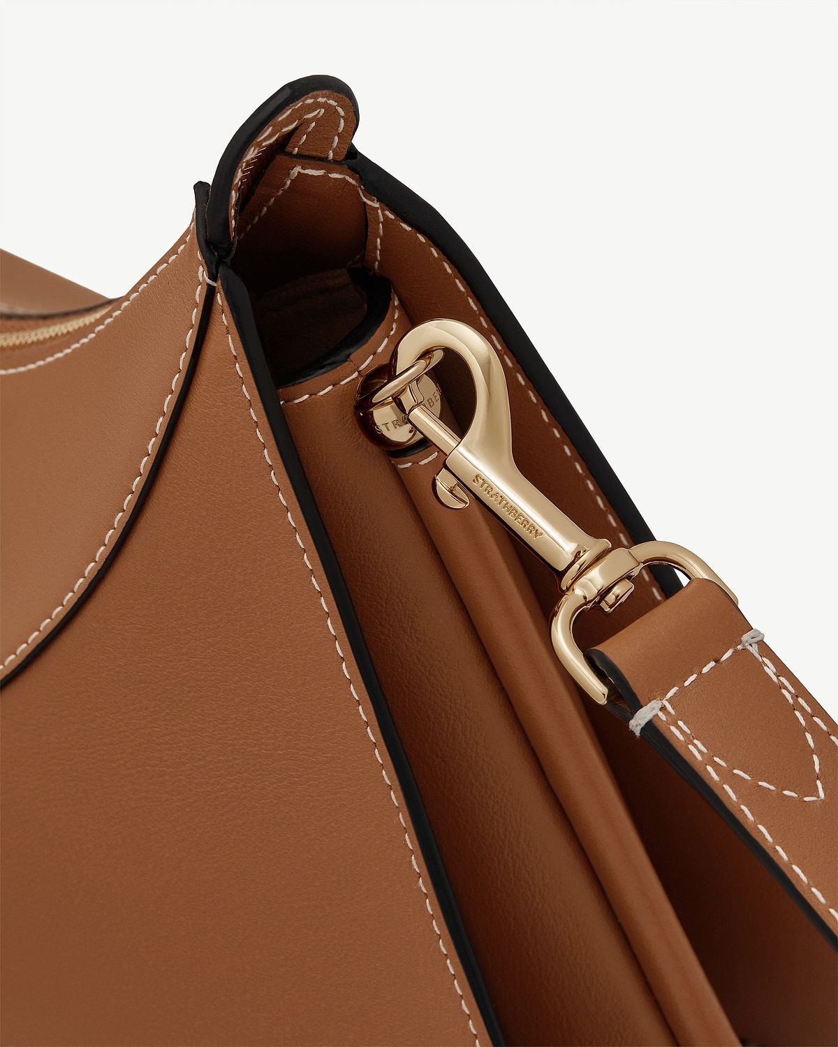 Detail of tan leather Nest Shoulder bag showing stitched edge and gold Strathberry clasp.