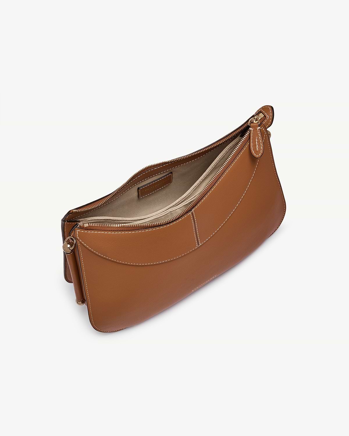 Tan leather shoulder bag with visible top zip, white stitching, curved front pocket.