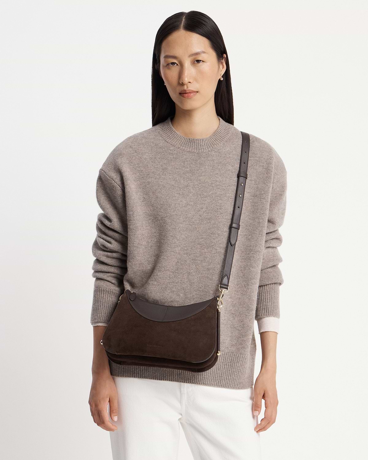 Model wearing Nest shoulder bag in espresso suede with adjustable strap across chest.
