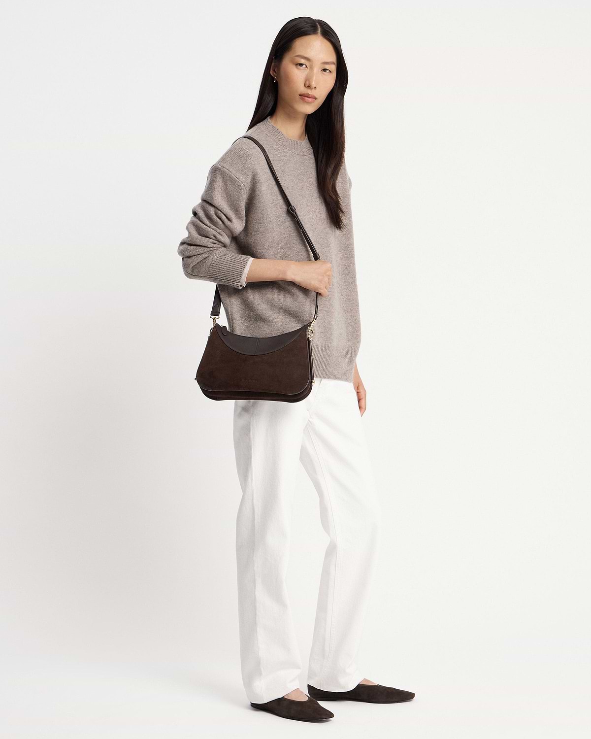 Model wearing a shoulder bag in espresso suede over left shoulder.