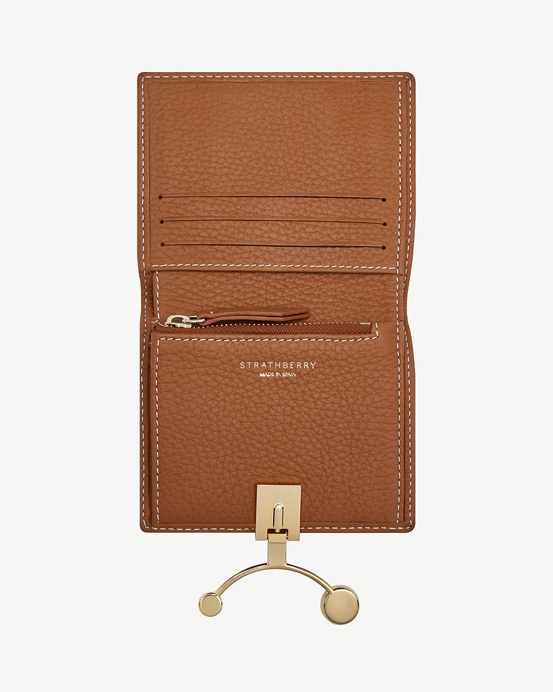 Tan leather crescent wallet open with card slots, zip pocket, vanilla stitching and Strathberry logo.