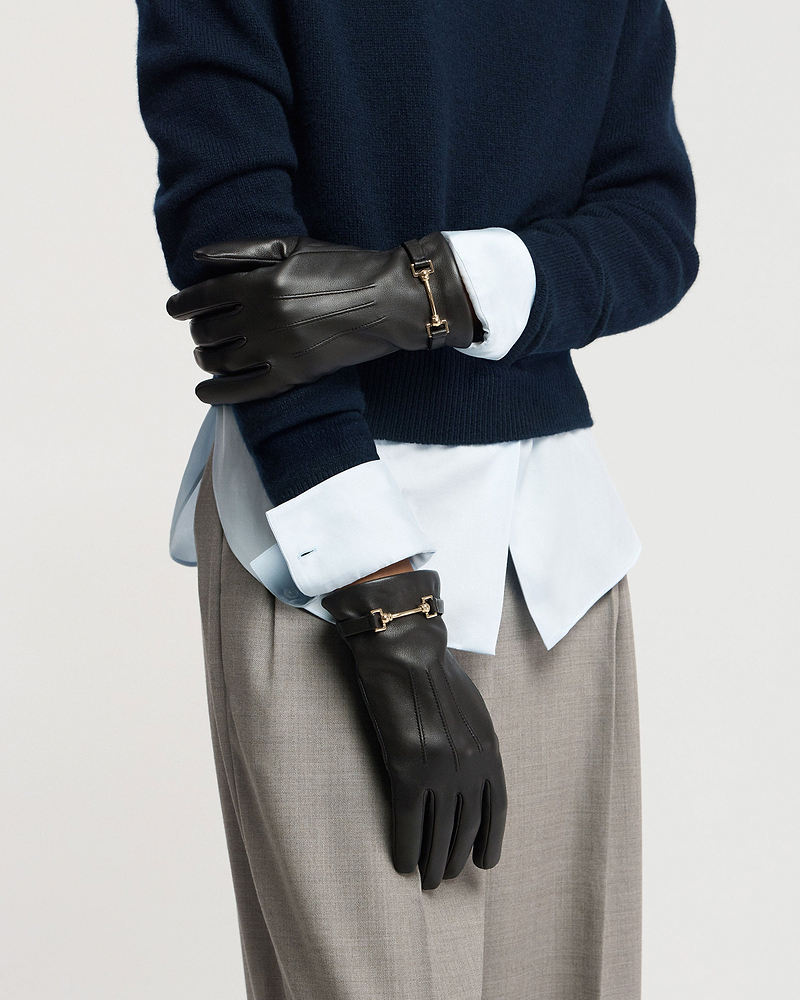 Black leather gloves with gold horsebit detail worn with navy jumper and shirt.