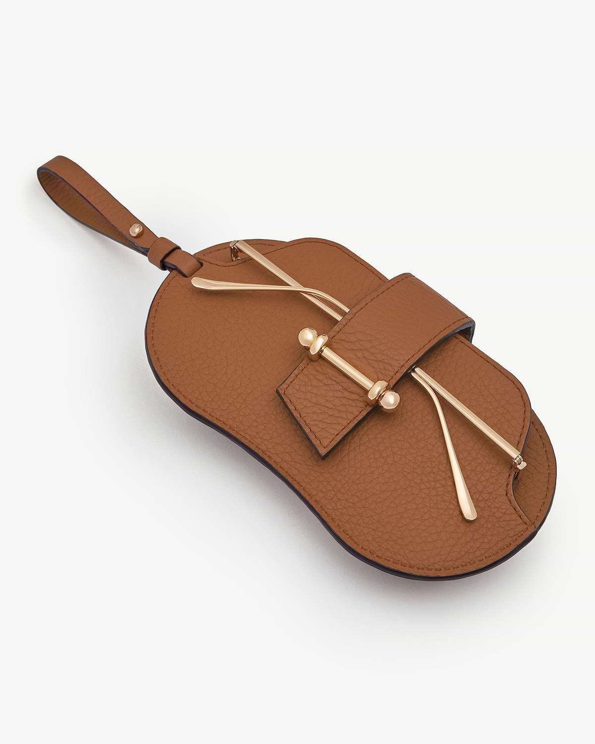 Tan pebbled leather sunglasses case with wrist strap and gold-tone bar detail.