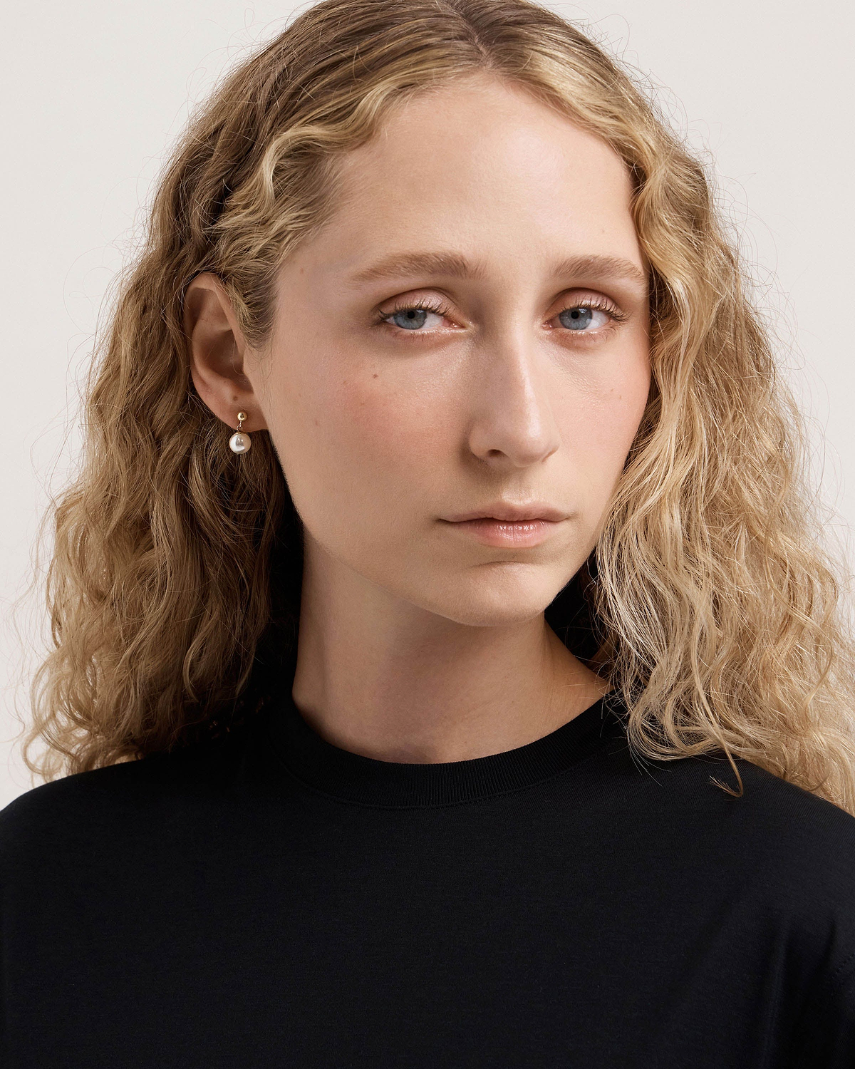 Model wearing 24-carat gold gilded pearl drop earrings, head and shoulders visible.