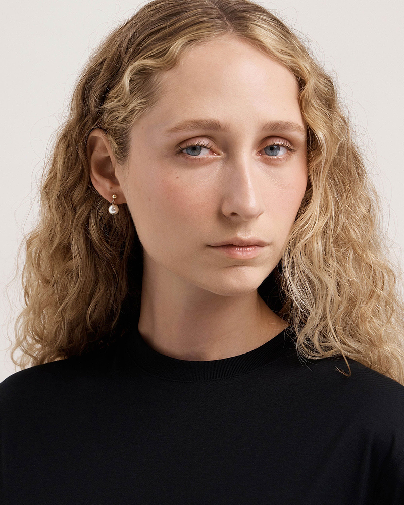 Model wearing 24-carat gold gilded pearl drop earrings, head and shoulders visible.