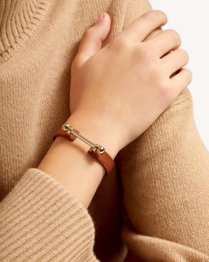 Chestnut leather music bar bracelet with 22-carat gold-gilded bar and ball ends on wrist