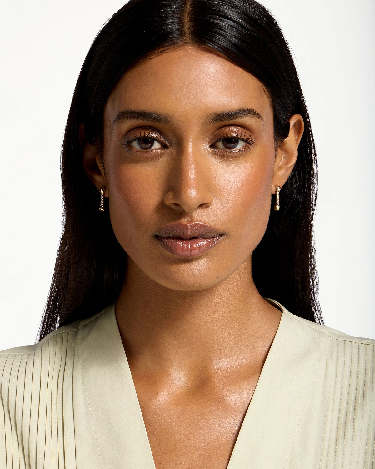 Woman wearing 22 carat gold gilded crystal mosaic drop earrings, front-facing headshot