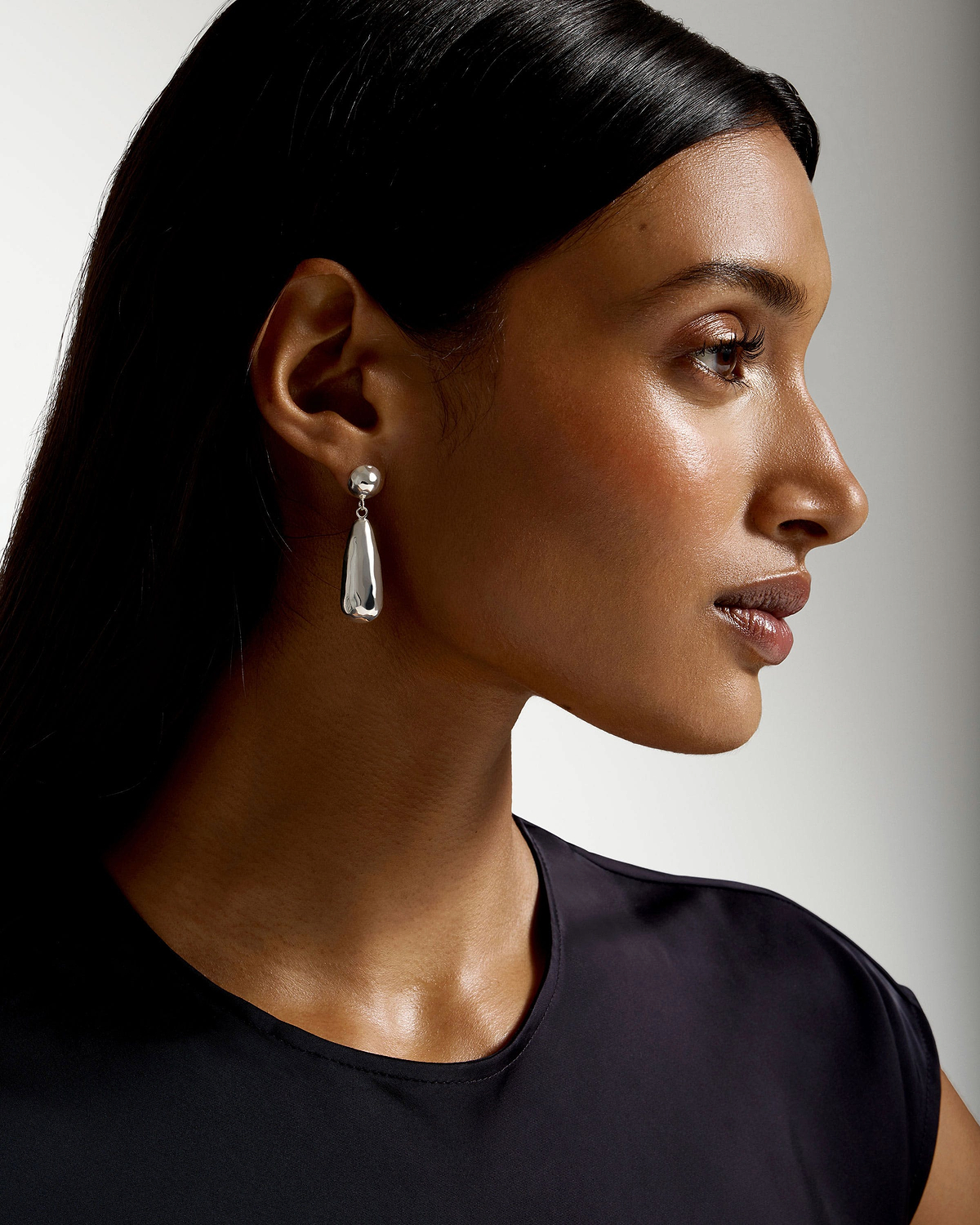 Profile of a model wearing sterling silver Jasmine drop earrings and a black top.
