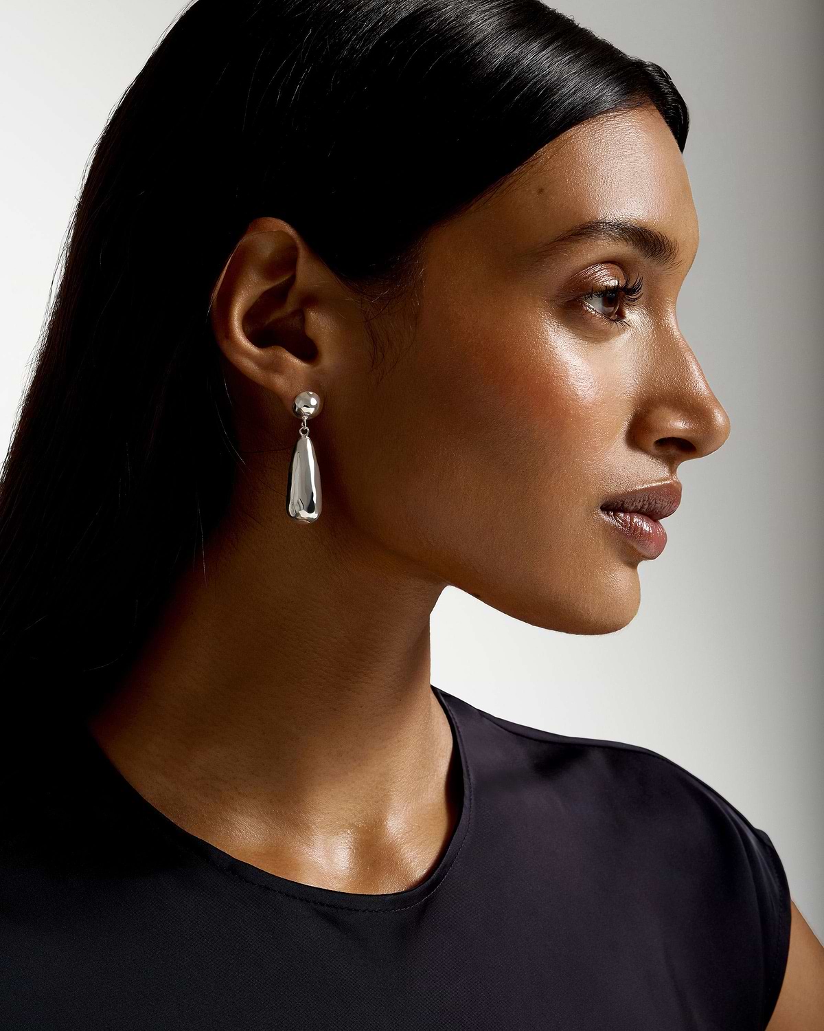 Profile of a model wearing sterling silver Jasmine drop earrings and a black top.